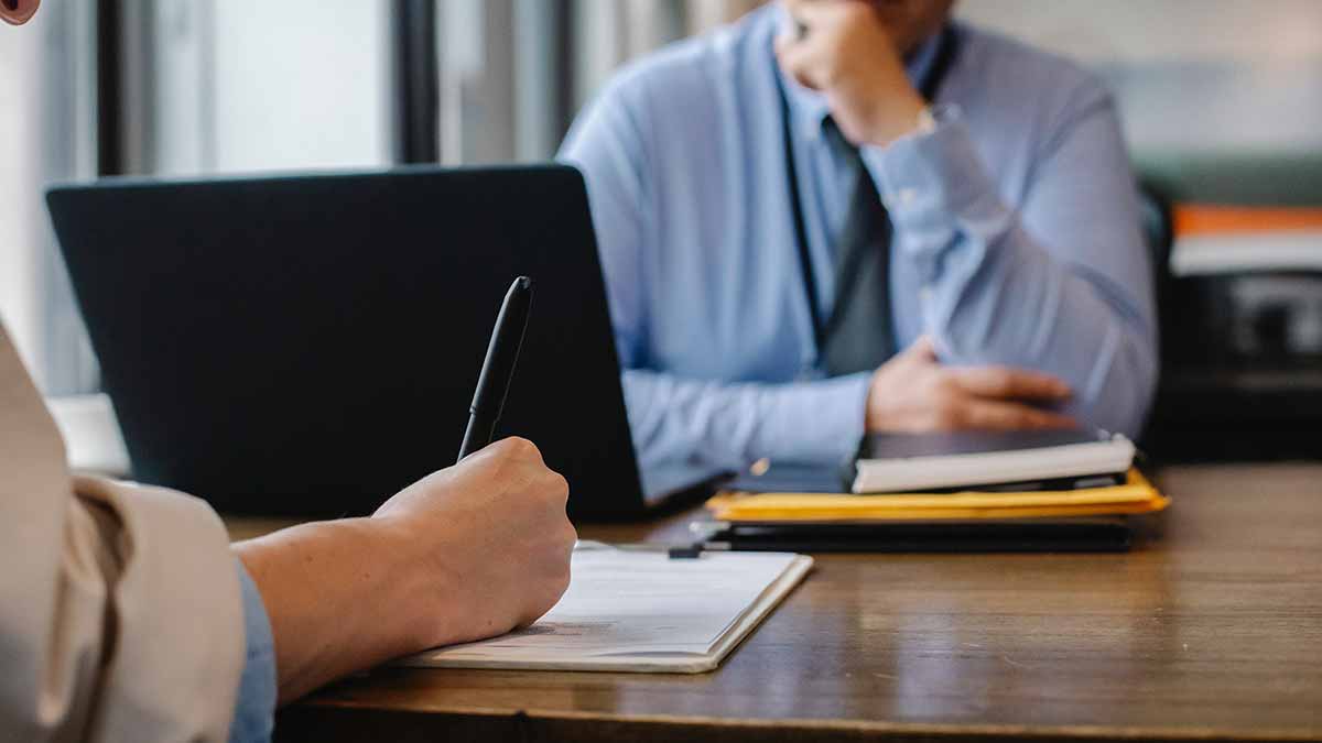 Una persona sentada frente a otra que está escribiendo