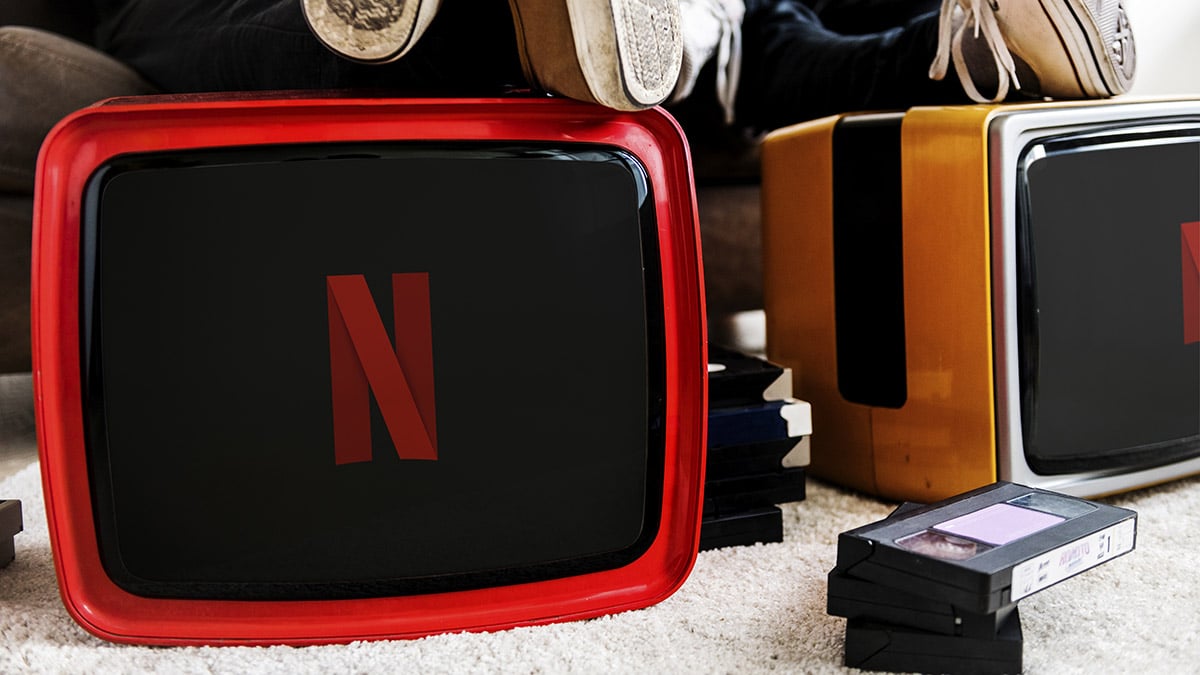 Two man sitting next to retro televisions